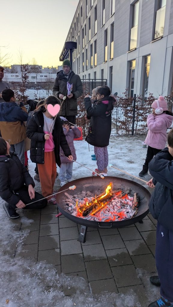 Kinder der GU Osteweg stehen mit Marshmallows um ein Lagerfeuer 